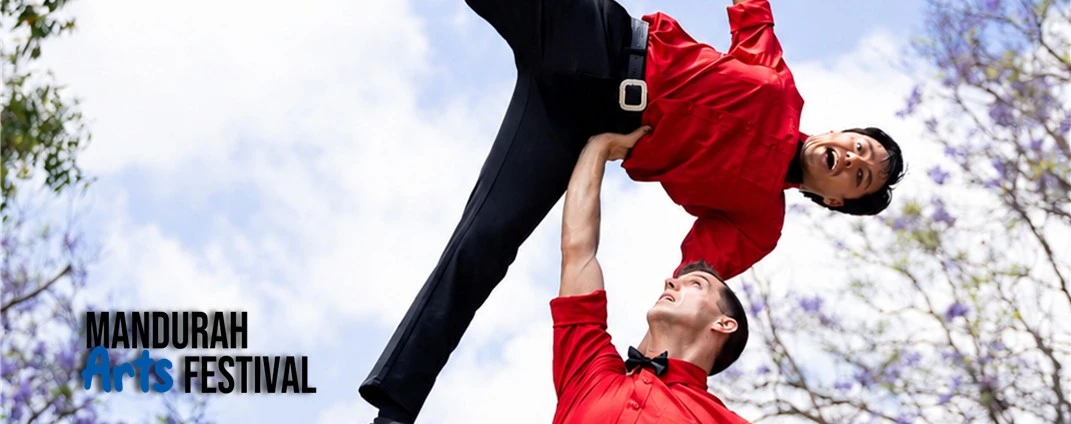 One man holds another man up in the air with only one hand in an acrobatic display